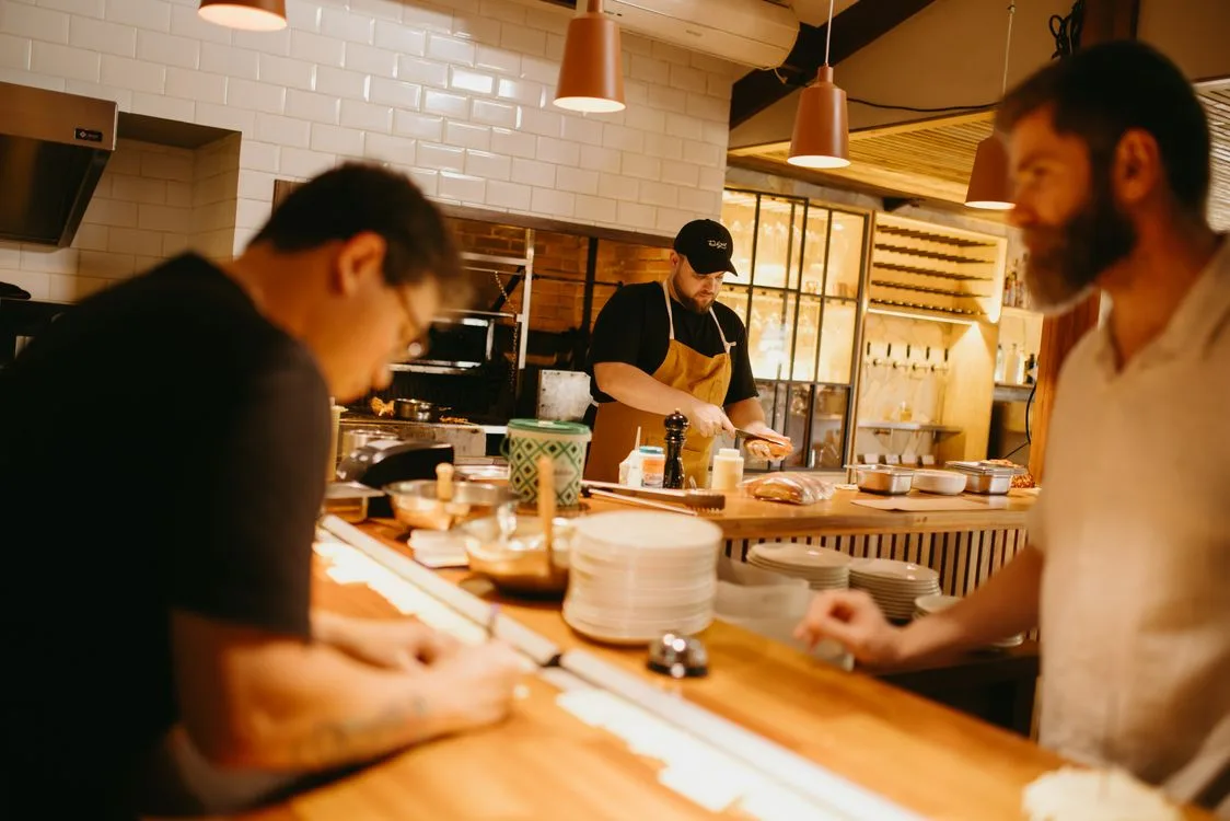 Restaurant team preparing food at an open kitchen counter during service.